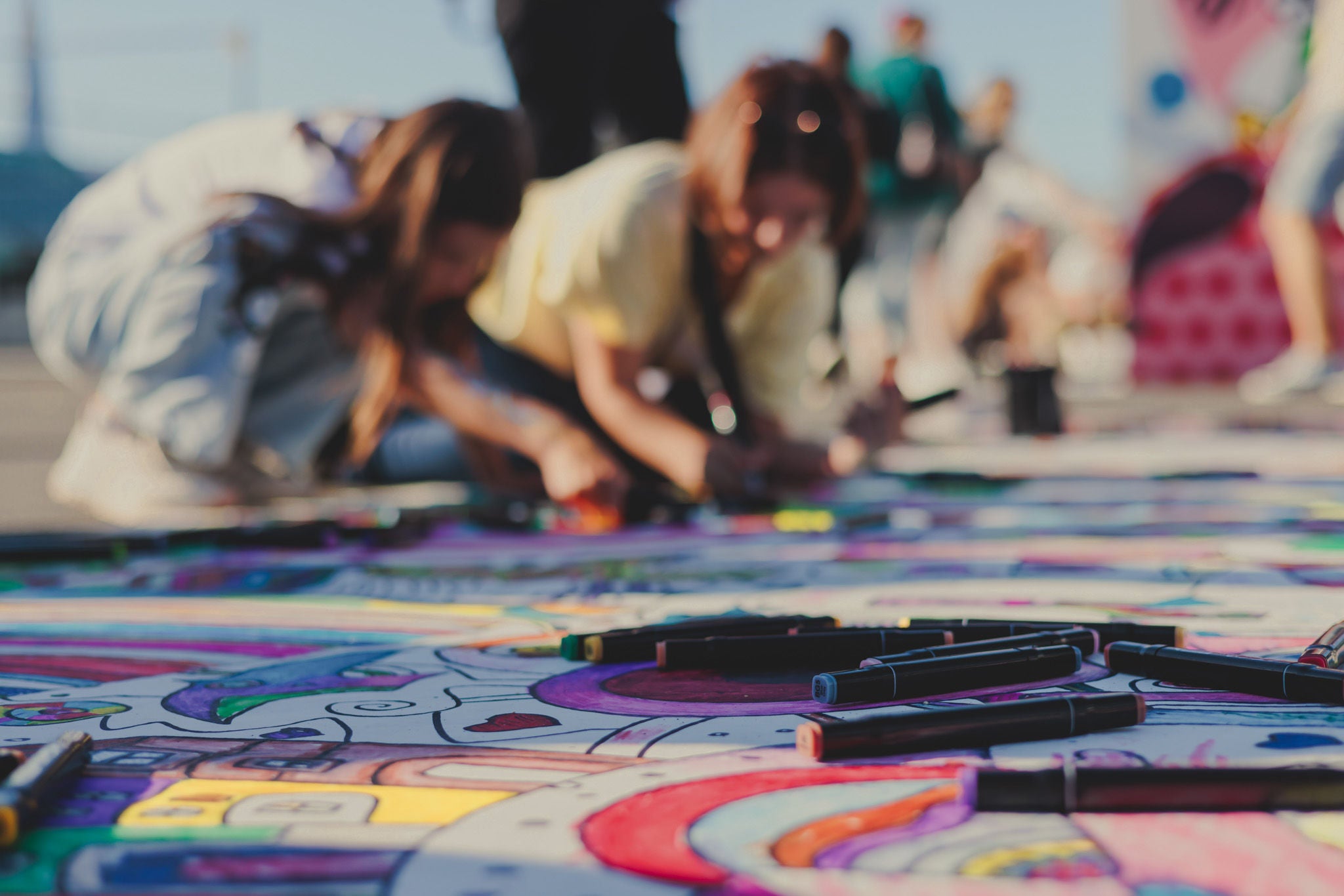 Process of drawing on asphalt and pavement, kids and children with crayons, chalk and markers, teens creating street art on the ground, graffiti and pictures on sideways, street painting festival