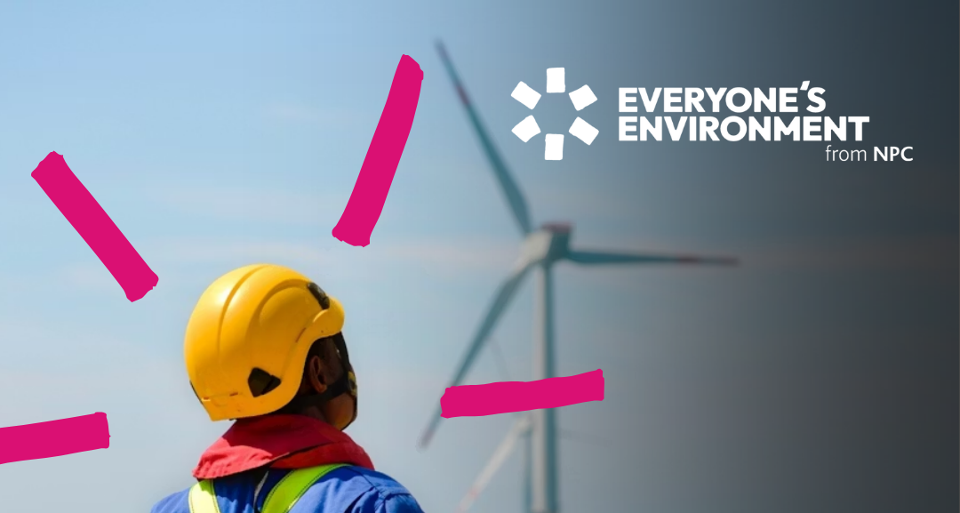 Back view of person in helmet looking at wind turbine.