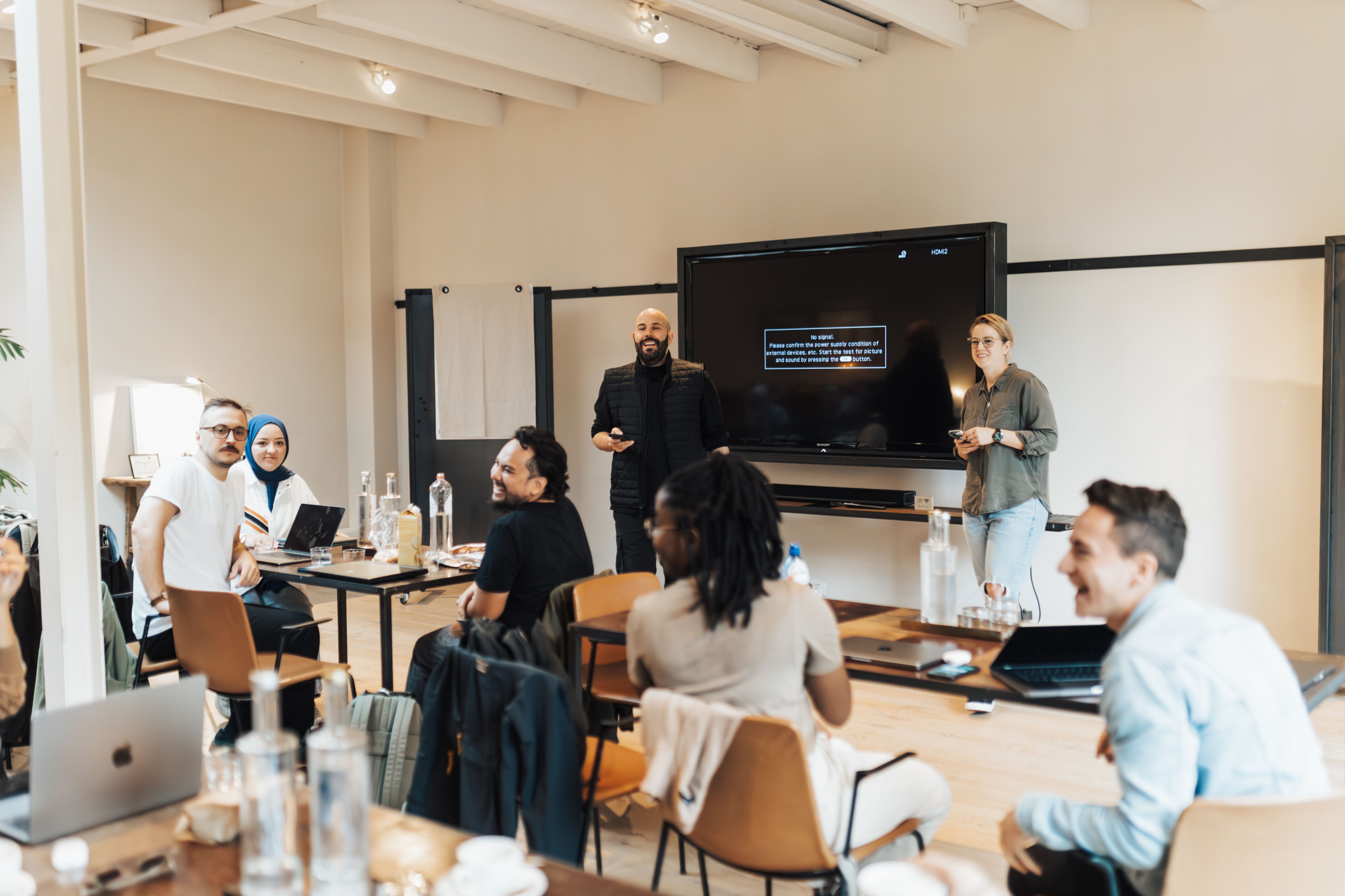 Image of a group of people presenting, listening and smiling.